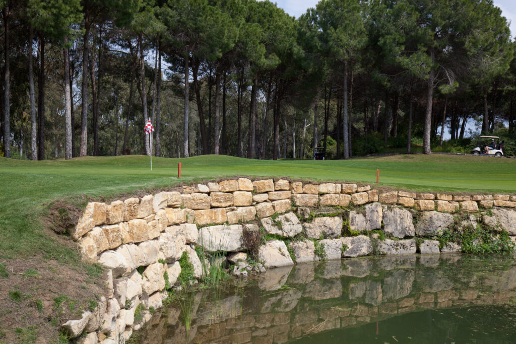 A hole with a stone wall and trees in background at The Pasha Golf Course