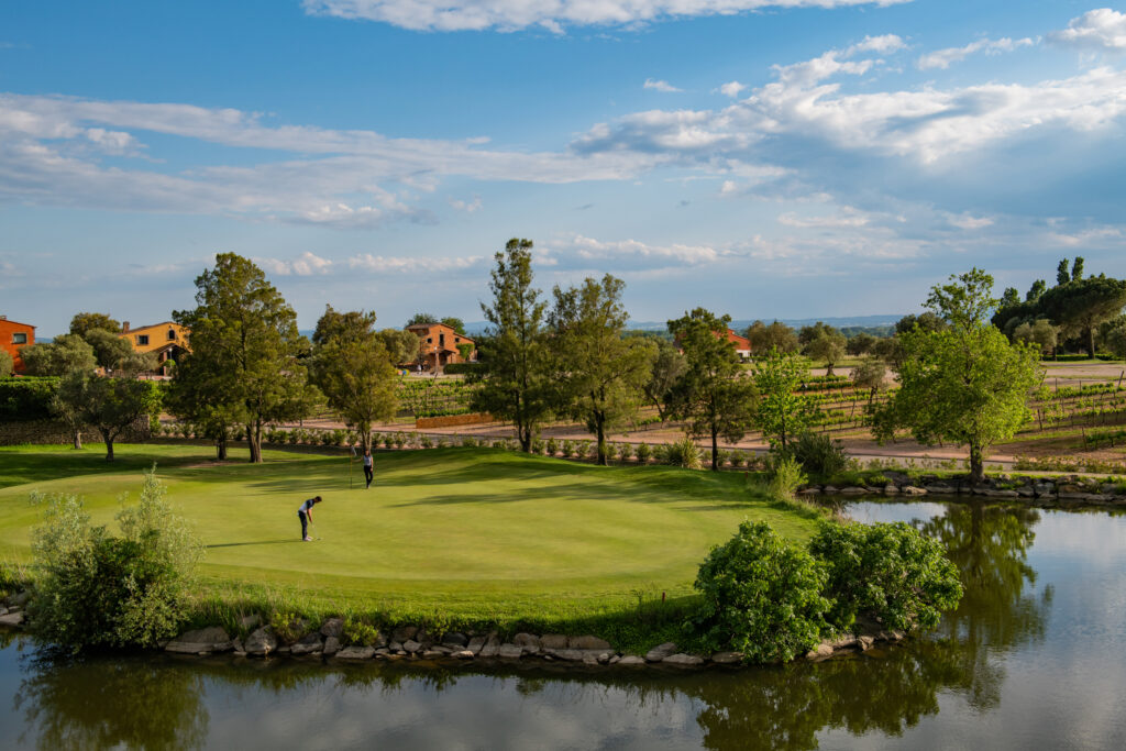 People playing golf at Peralada Golf Course with lake nearby