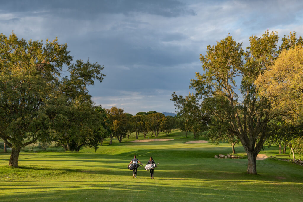 People walking through the fairway with bunkers and trees in distance