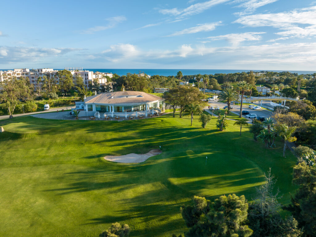 A green with bunker and clubhouse in background at Alto Golf Course