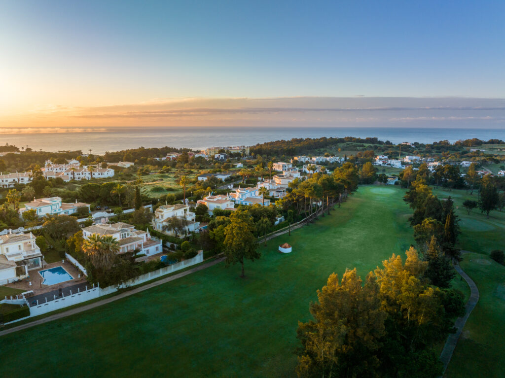 A fairway with buildings and ocean in background at sunset at Alto Golf Course