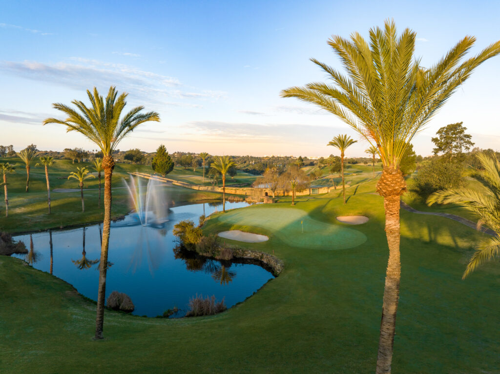 Fairway with water hazard with sprinkler on surrounded by palm trees at Gramacho Golf Course