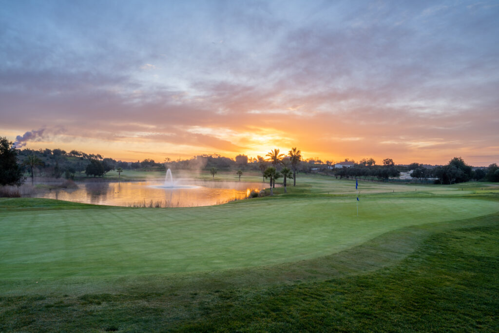 A green with a lake in the background with fountain at sunset at Silves Golf Course