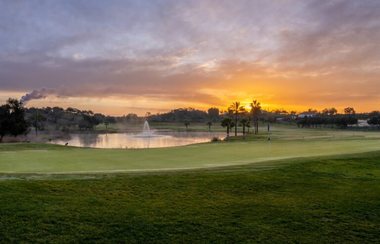 A green with a lake with water fountain in background at sunset at Silves Golf Course