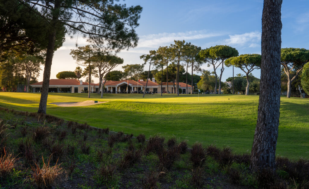 A green with clubhouse in background with trees around at Vila Sol Golf Course