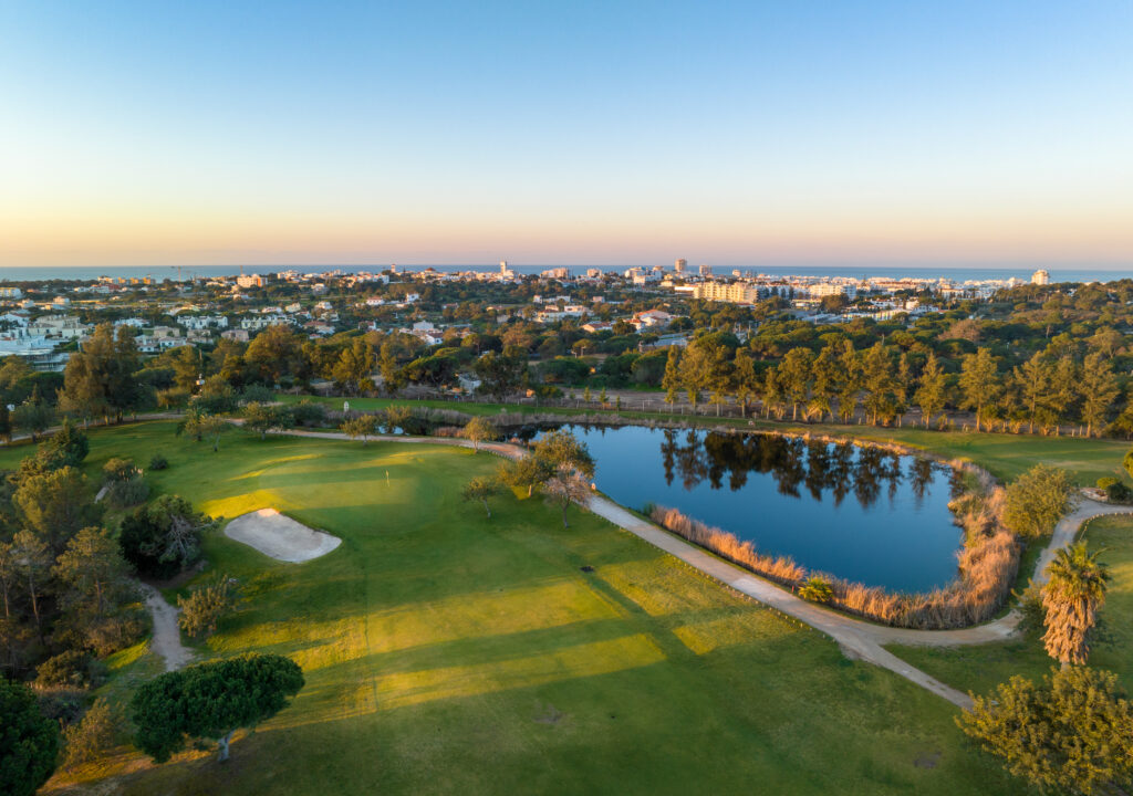 Aerial view of Vila Sol Golf Course with lake and buildings in distance