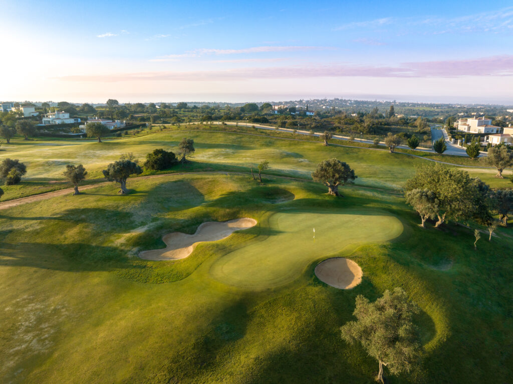 A green with bunkers either side and trees in the background at Pinta Golf Course