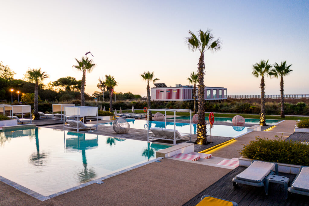 Outdoor pool view with palm trees at sunset at Pestana Alvor South Beach