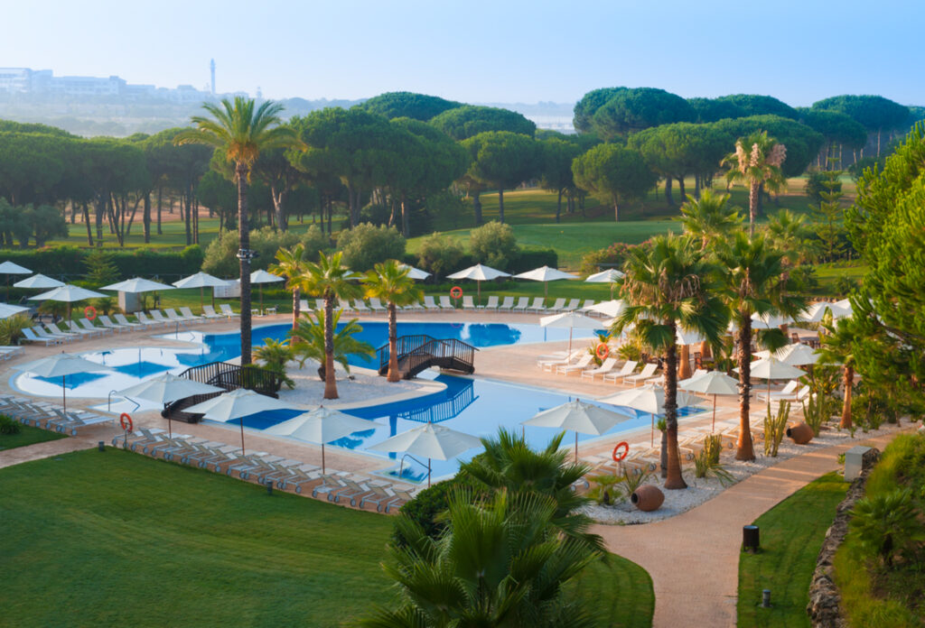 Outdoor pool at Precise Resort El Rompido with sun loungers and trees around