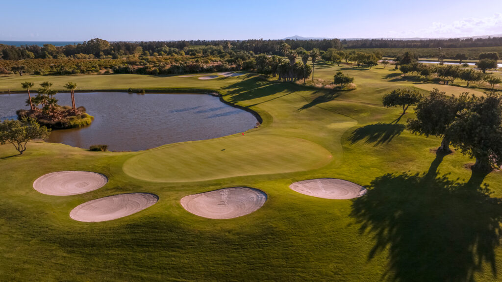 A green with four bunkers around it and a lake at Quinta da Ria Golf Course