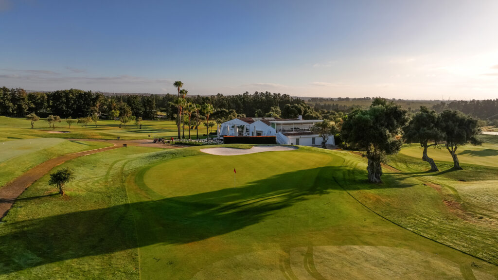 A green at Quinta da Ria Golf Course with clubhouse in background