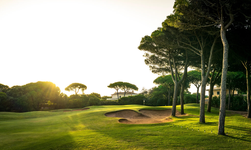 Fairway with bunkers and sun shining through trees at Onyria Quinta da Marinha Golf Course