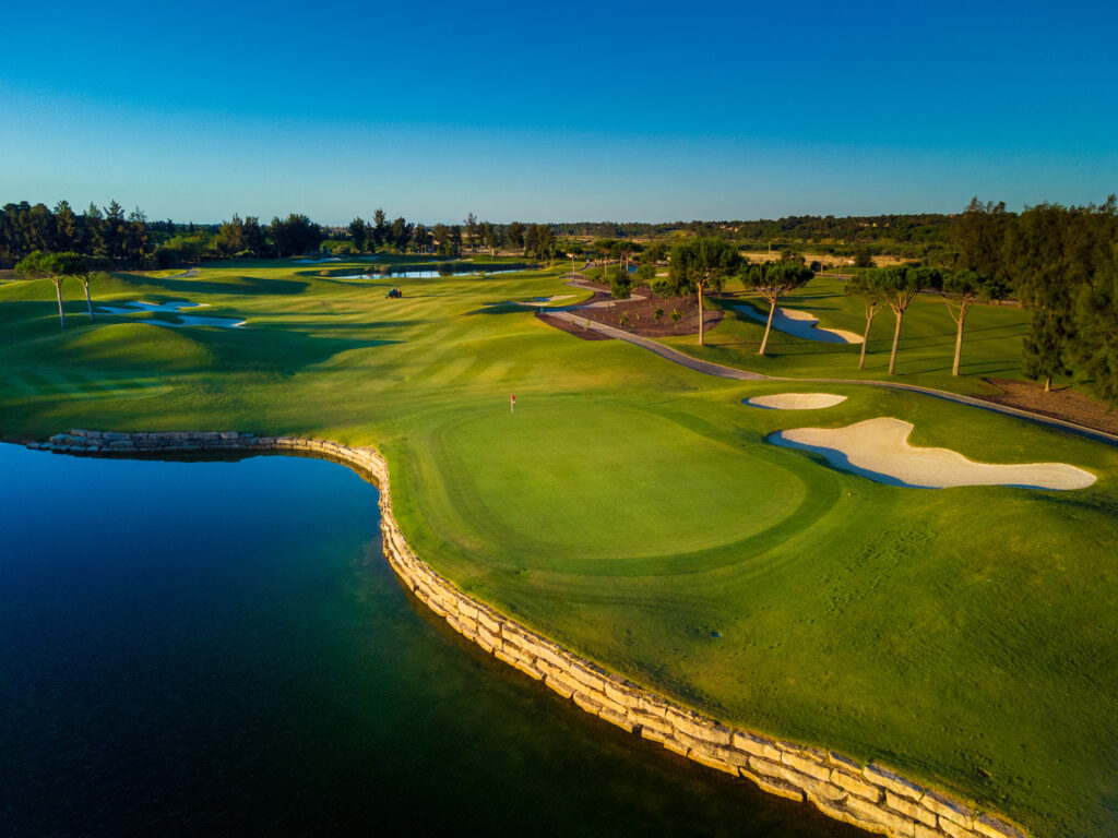 Aerial view of a lake with a green and bunkers next to it at Quinta Do Lago Laranjal Golf Course