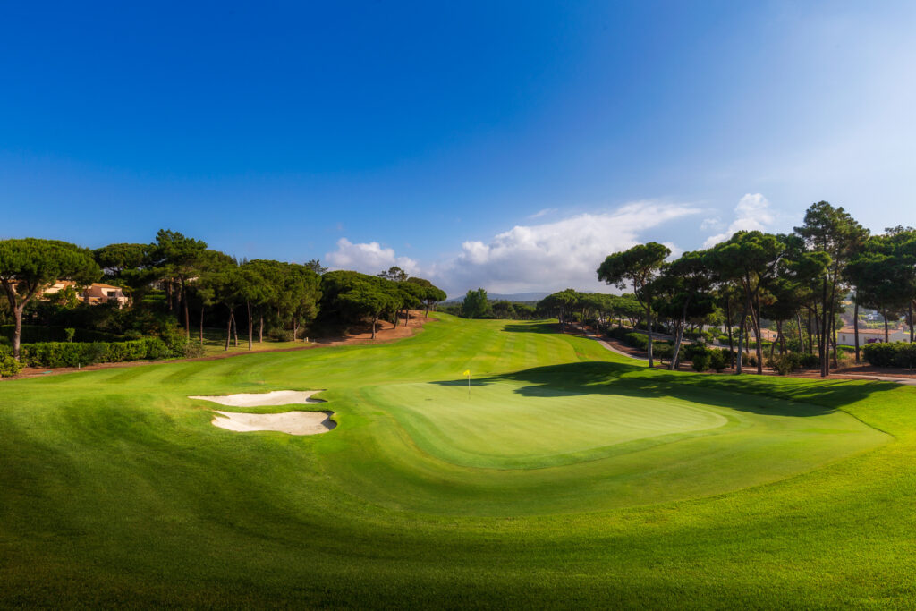 A green with a bunker next to it and trees around it at Quinta Do Lago North Golf Course