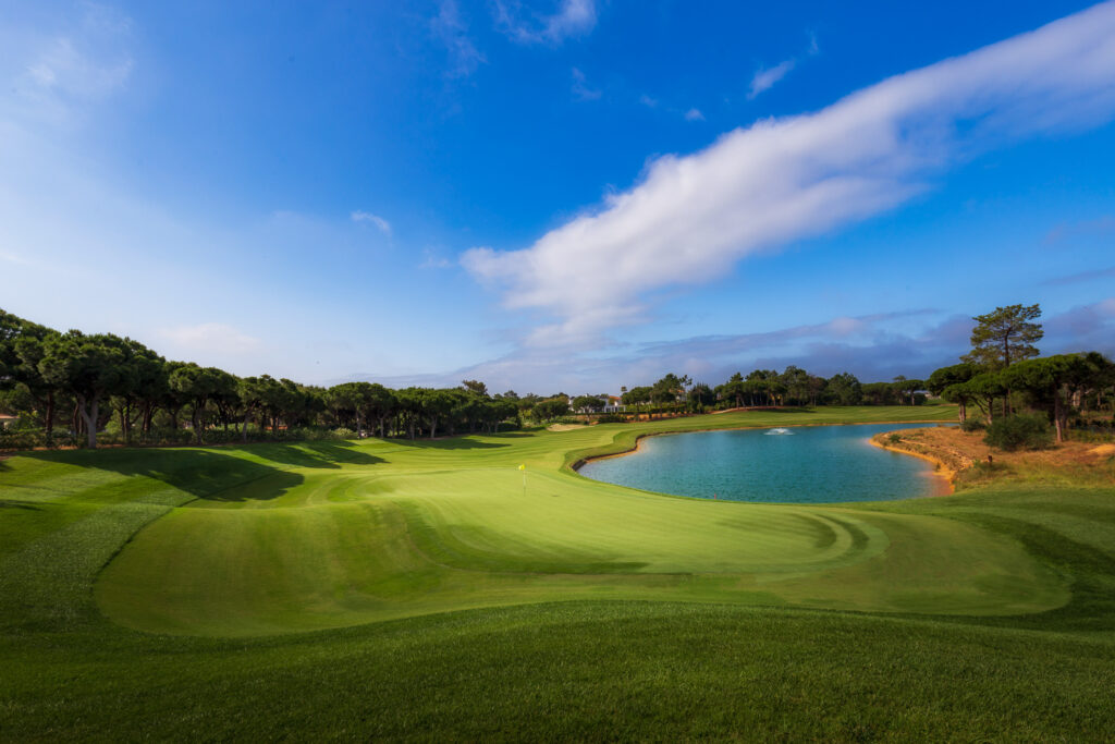 A green with a lake next to it and trees around at Quinta Do Lago North Golf Course