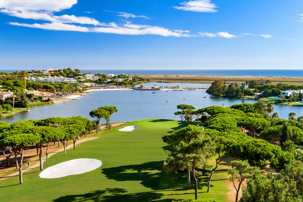 Aerial view of Quinta Do Lago South Golf Course with a lake and beach in the background