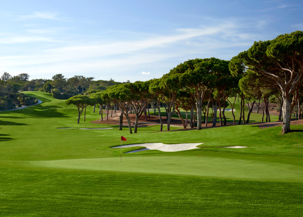 A green with a bunker and trees around at Quinta Do Lago South Golf Course