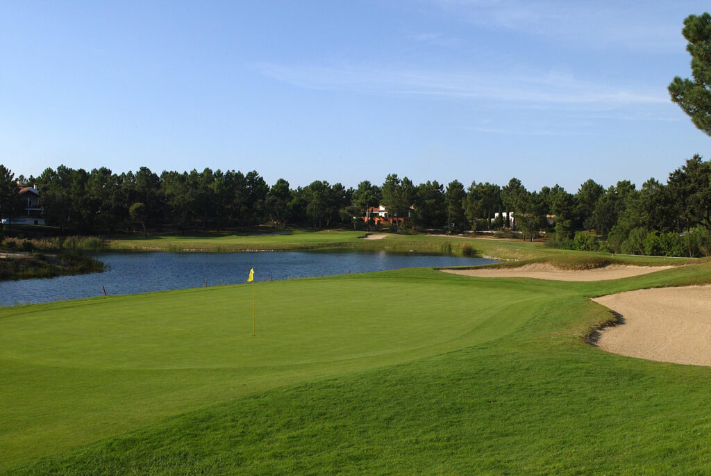 Hole with yellow flag with lake in background at Quinta do Peru Golf Course