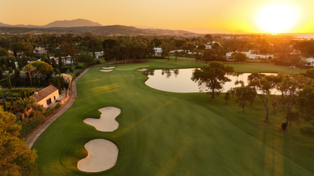 Fairway with bunkers and lake at Real Club Valderrama Golf Course at sunset