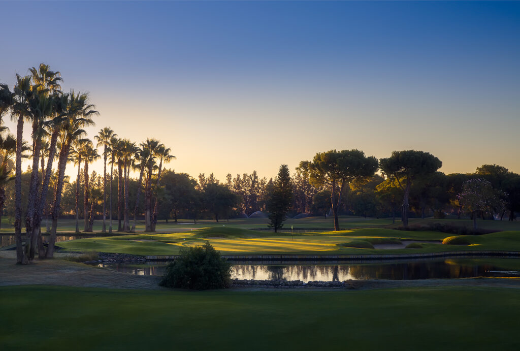 Fairway with lake and palm trees around at Real Club Sevilla Golf