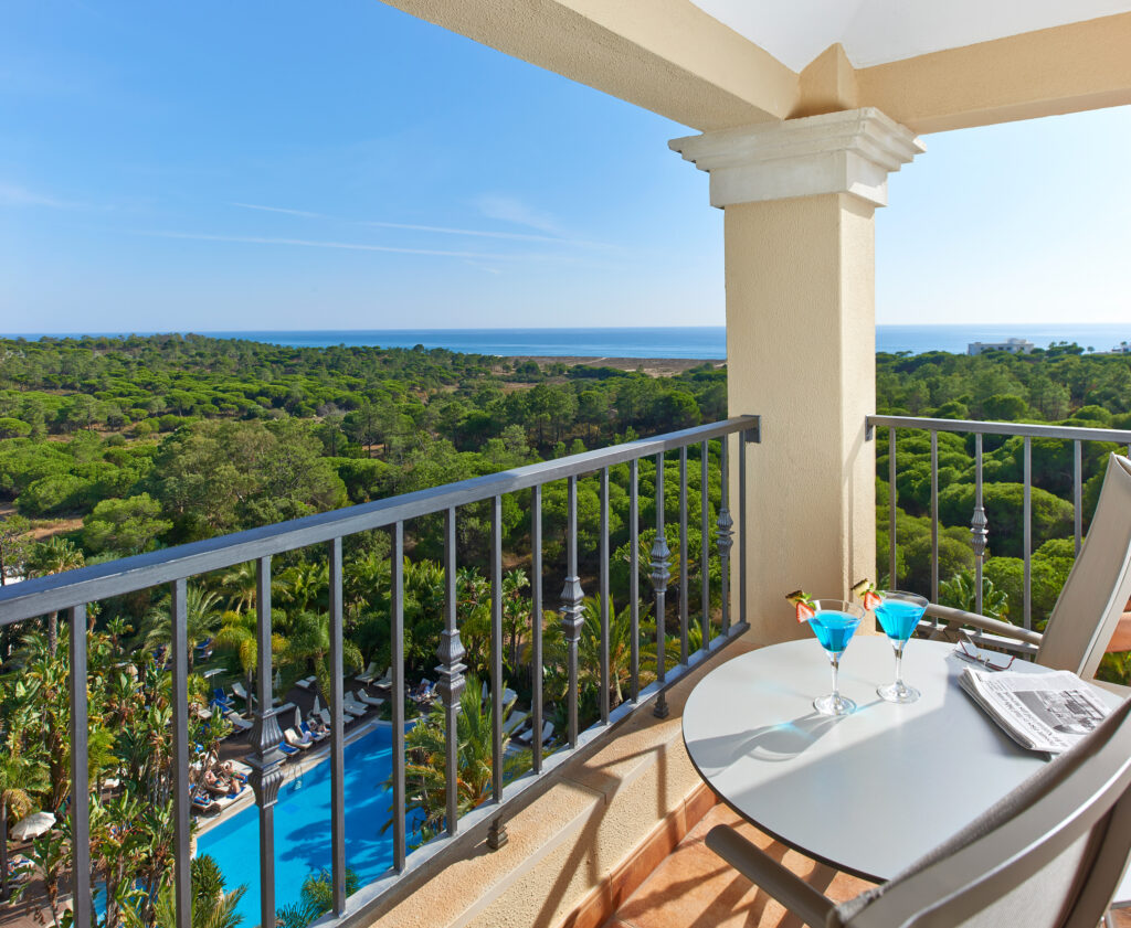Chairs and table on balcony overlooking outdoor pool and surround views at Ria Park Hotel & Spa
