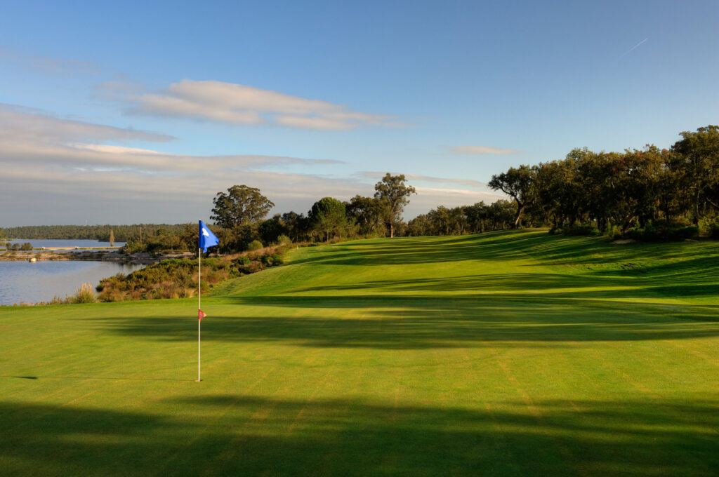 Hole with blue flag and trees around with lake to the side at Ribagolfe Lakes Golf Course