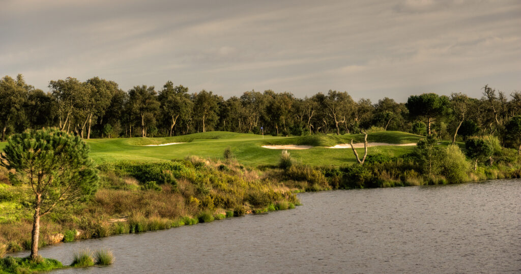 Lake with hole and bunkers and trees in the background at Ribagolfe Lakes Golf Course