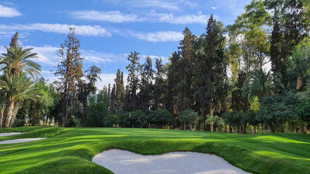 Hole with bunkers around at Royal Golf Marrakech with trees around