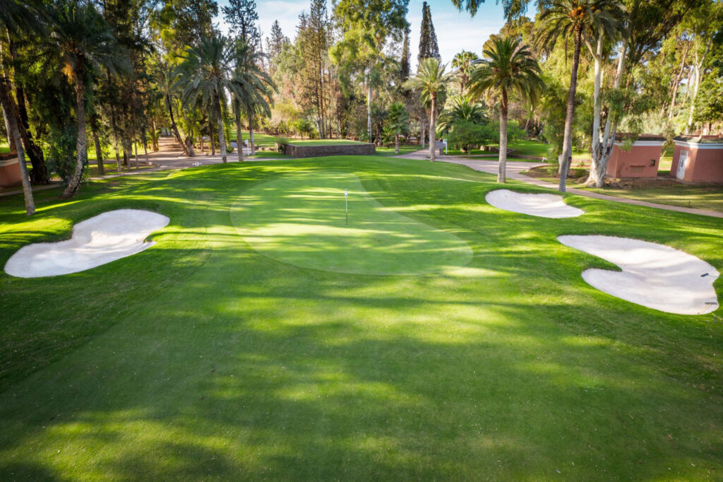 Hole with bunkers at Royal Golf Marrakech with trees around