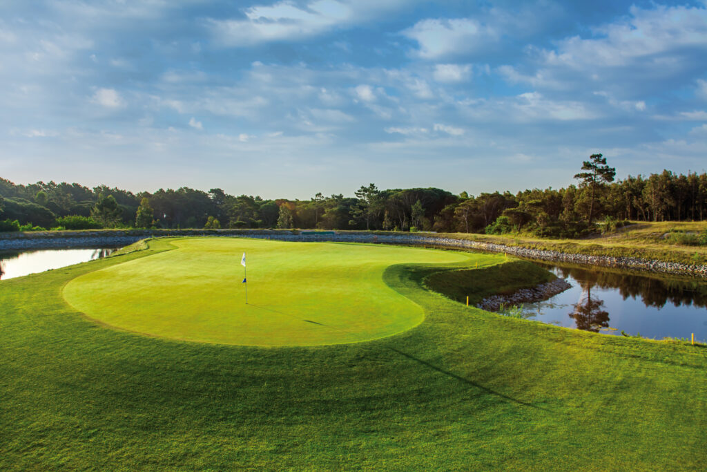 Green with water hazard around it and trees in background at Royal Obidos Golf Course