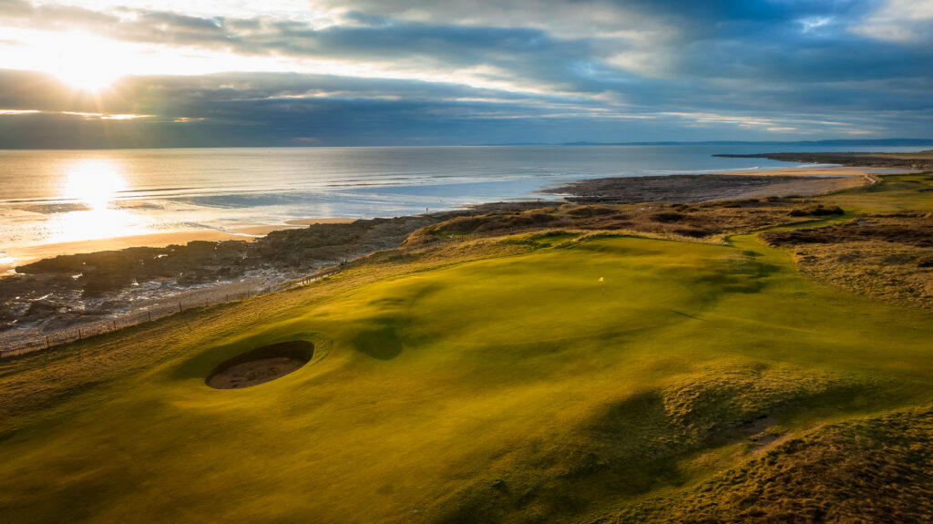 Hole with yellow flag and bunker at Royal Porthcawl next to the beach