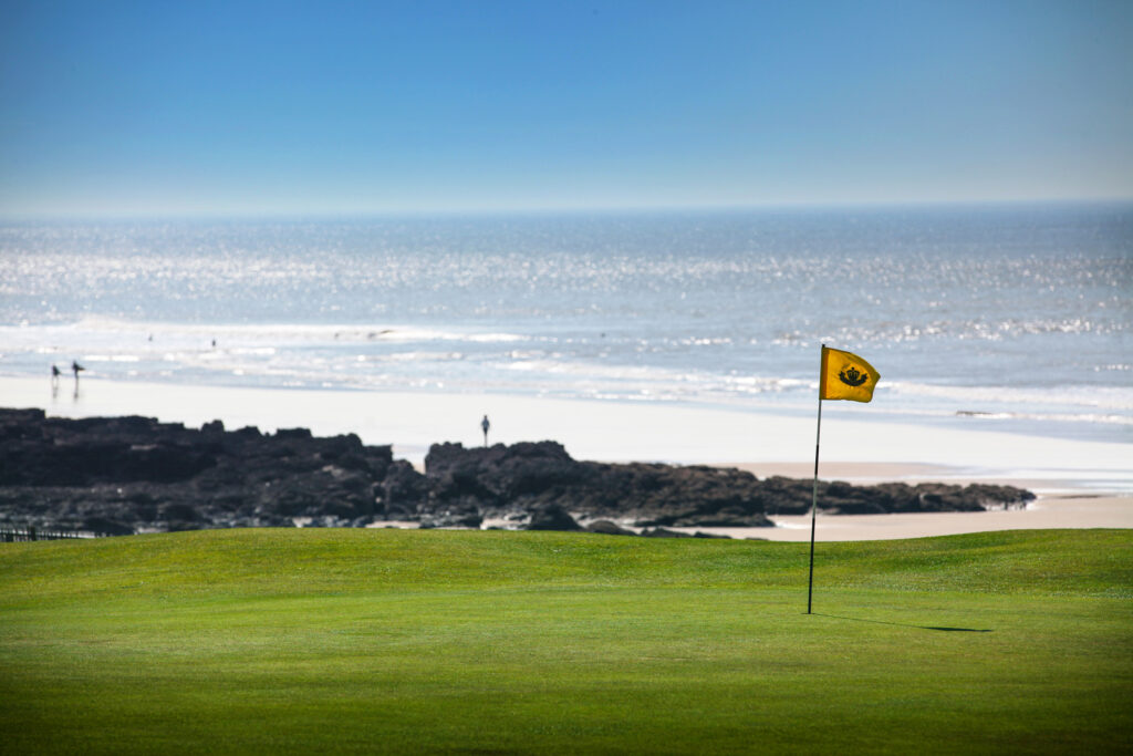 Yellow flag at Royal Porthcawl with ocean in background