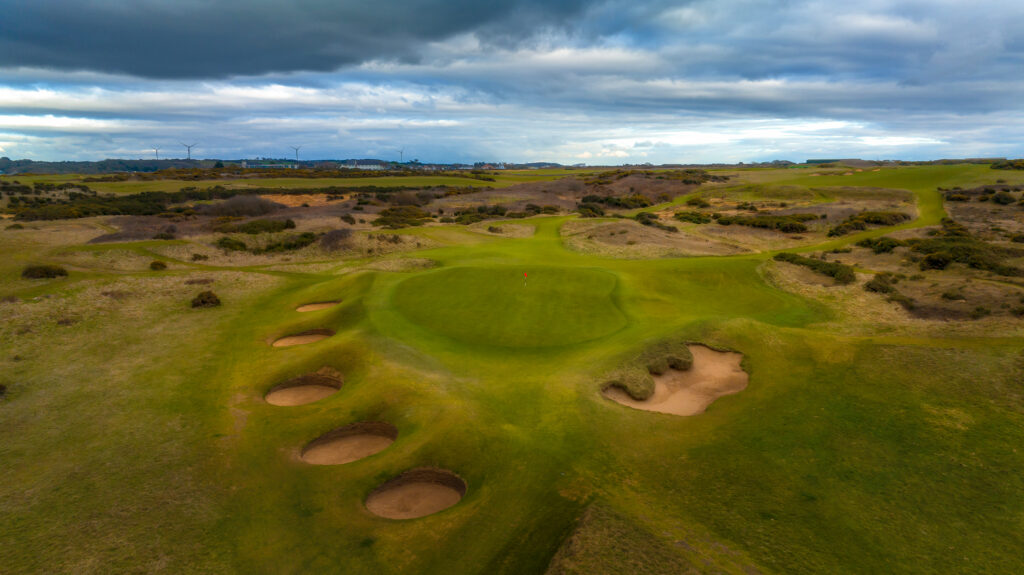 Aerial view of Royal Porthcawl with a hole with a red flag and bunkers