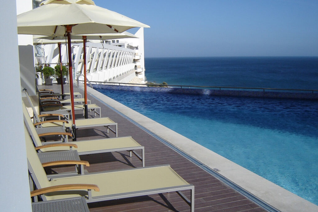 Sun loungers by outdoor pool at Sesimbra Hotel & Spa