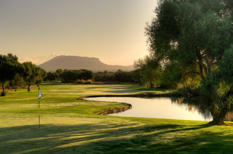 Lake by hole with trees around at Son Antem - East Course at sunset