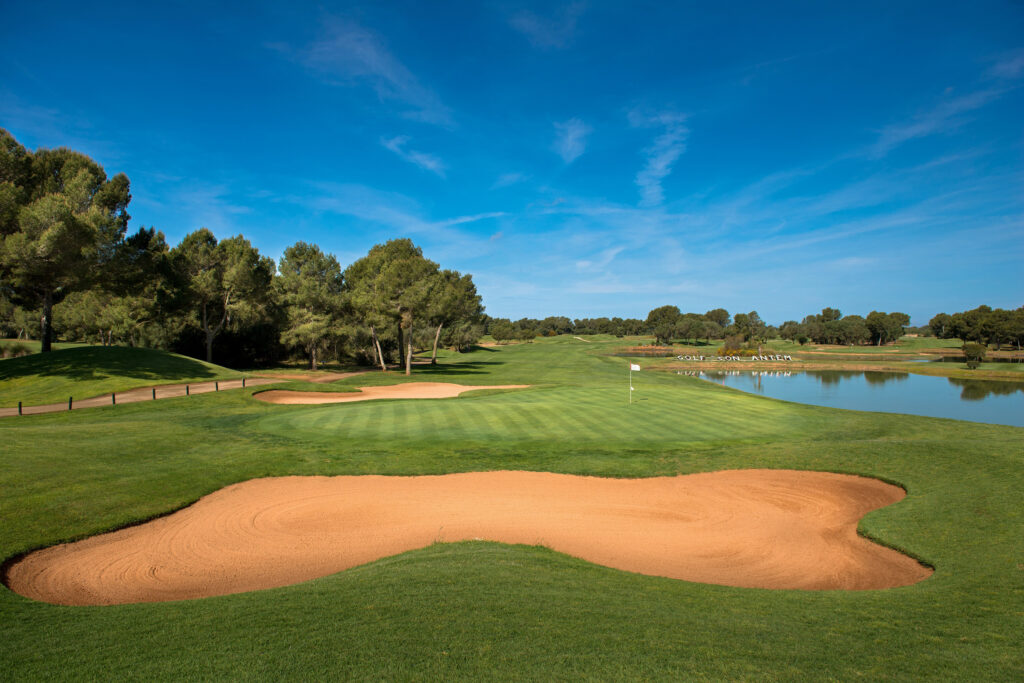 Bunker on fairway by a hole with trees and lake nearby at Son Antem - West Course