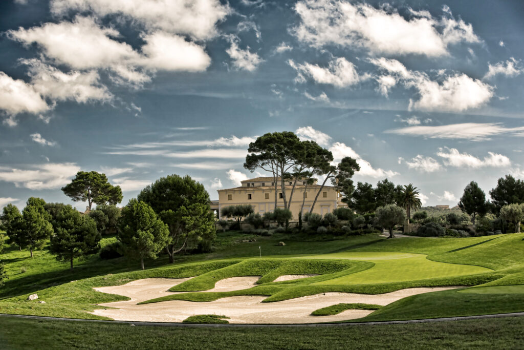 Hole with bunkers and trees and building in background at Son Gual Golf Course