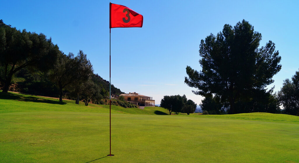 Hole with red flag with building in background at Son Termes Golf Course