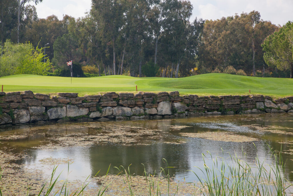 Lake with stone wall and fairway in background with trees around at PGA Sultan Golf Course