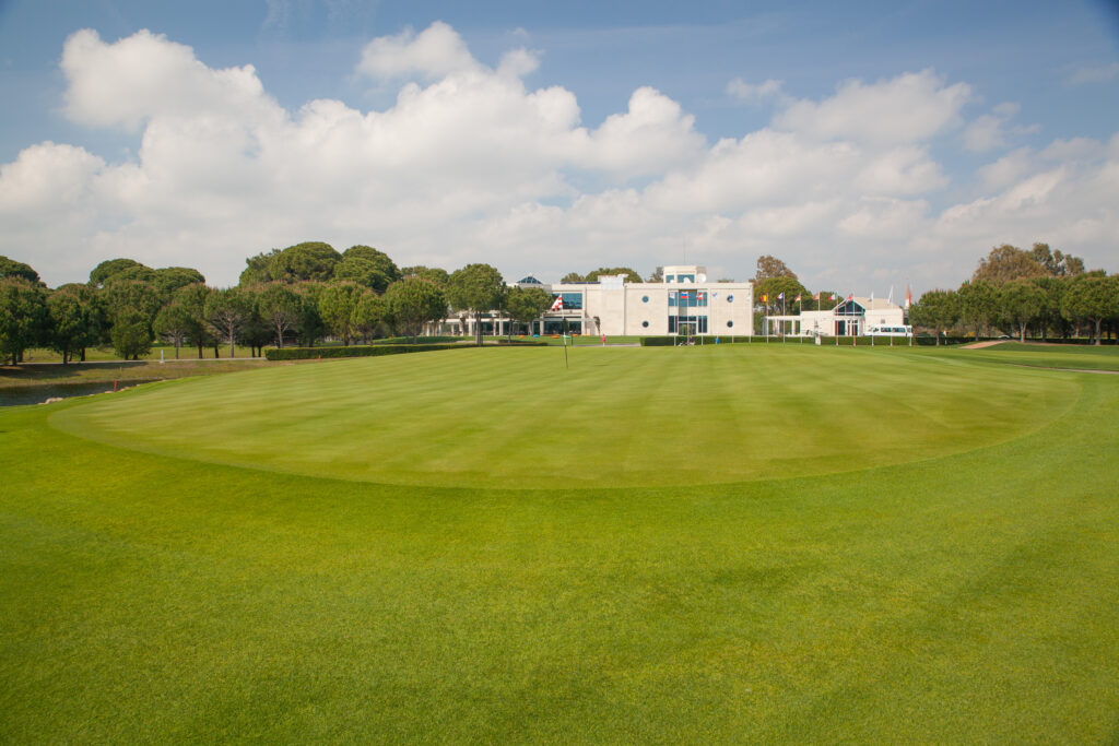 Hole with trees and building in background at PGA Sultan Golf Course