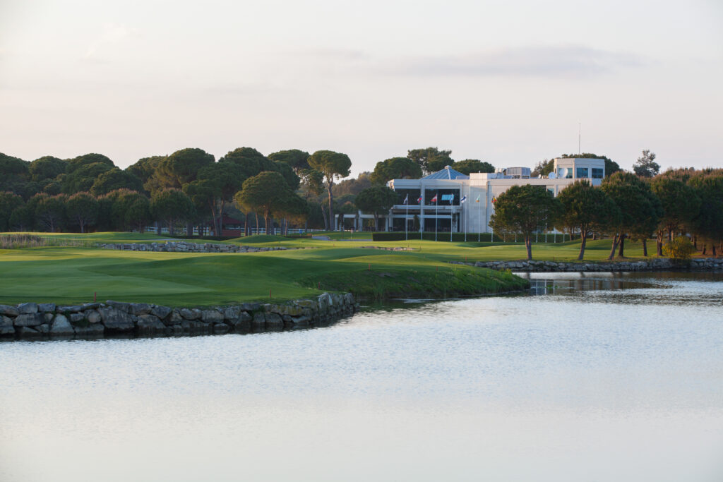 Lake with fairway and trees in background at PGA Sultan Golf Course with building