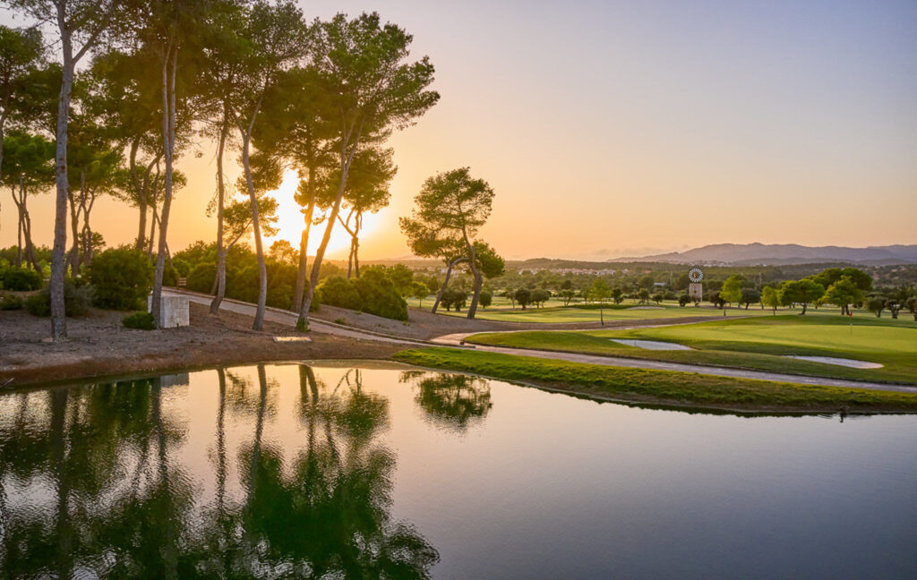 Lake on fairway with sun setting through the trees at T Golf Calvia Course