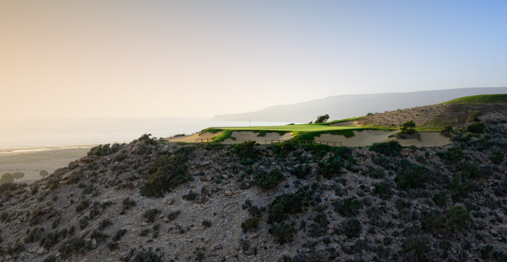 Aerial view of a hole surrounded by bunkers on hillside at Golf Taghazout