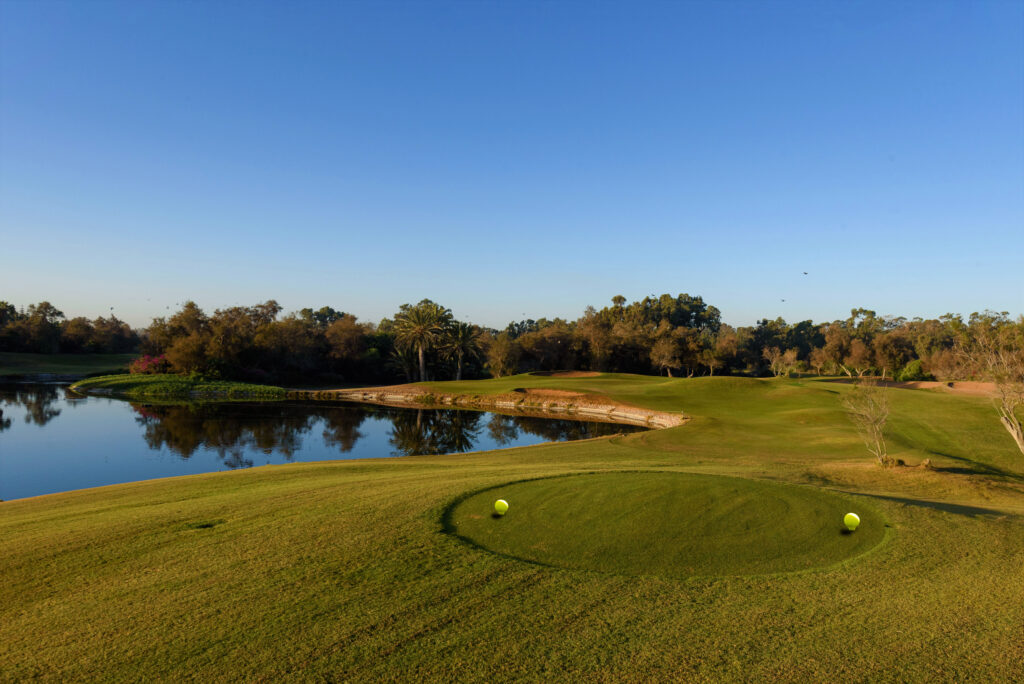 Tee box at Golf Taghazout next to a lake with trees in background