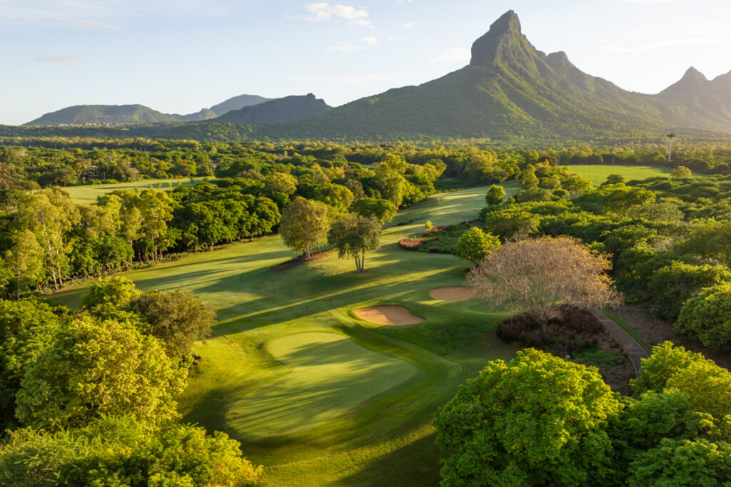 Hole with bunkers at Tamarina Golf Club with trees around and mountain in distance