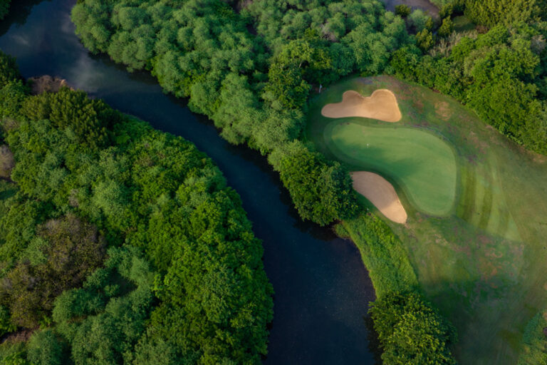 Birdseye view of river that runs through Tamarina Golf Club next to hole with bunkers