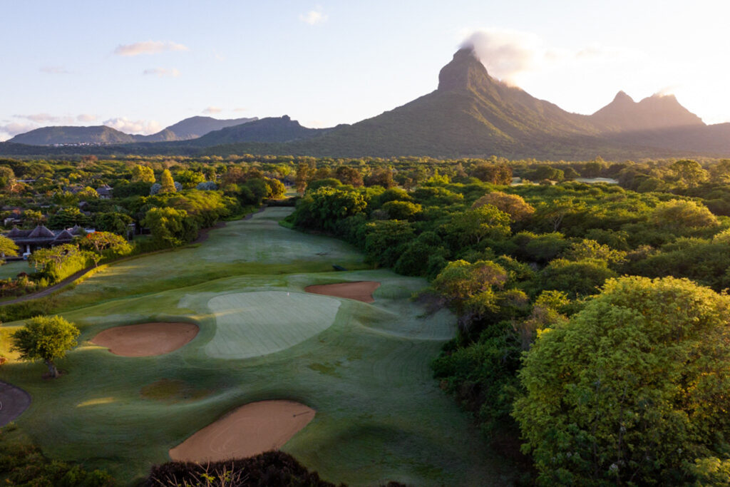 Hole with bunkers and trees around at Tamarina Golf Club with mountain in distance