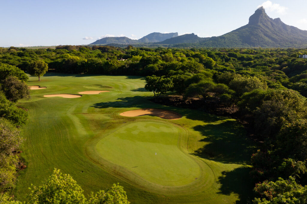 Hole with bunkers and trees around at Tamarina Golf Club with mountain in distance