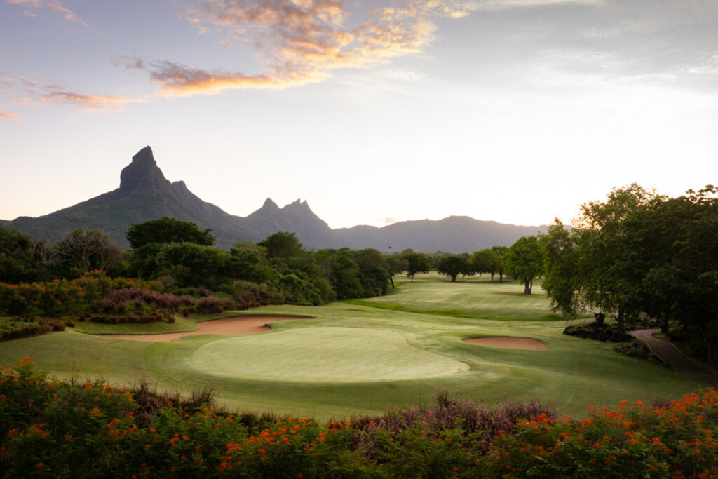 Hole with bunkers at Tamarina Golf Club with trees around and mountains in distance