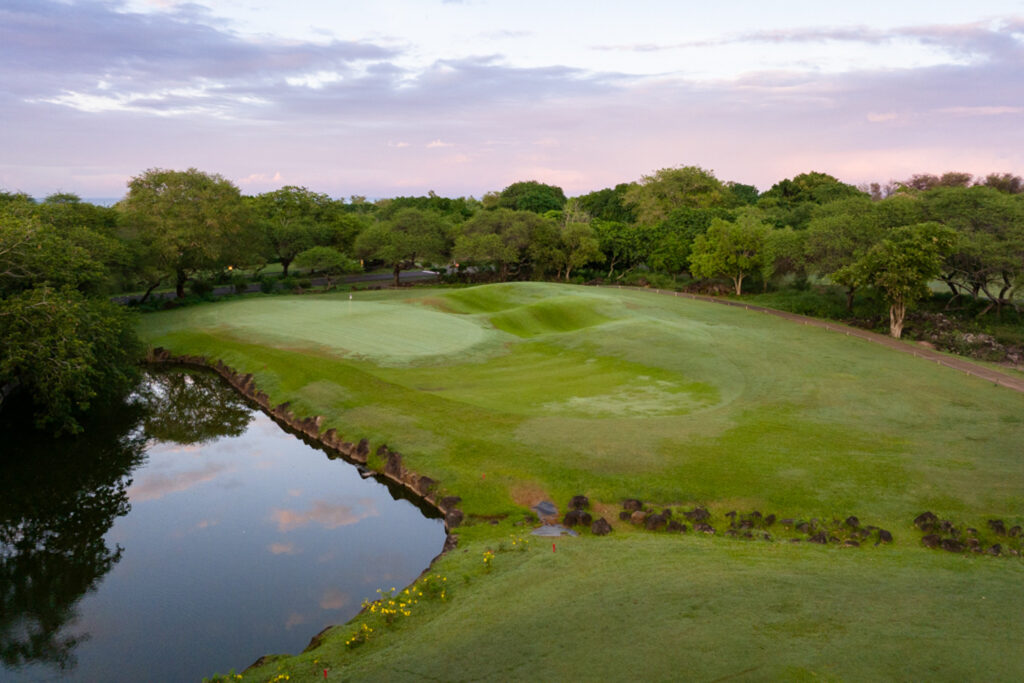 Hole with trees around and a lake next to it at Tamarina Golf Club